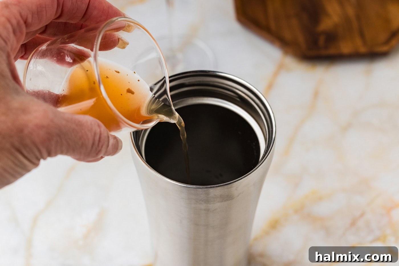 pouring olive juice into a cocktail shaker