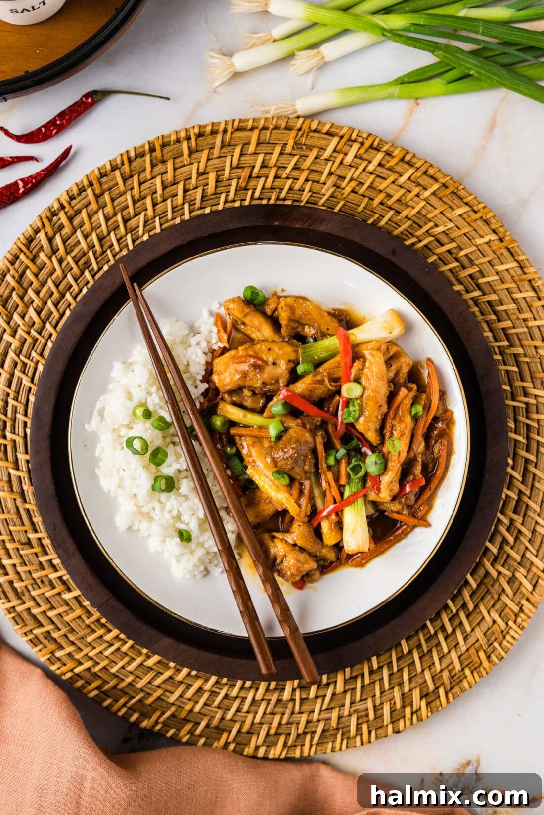A perfectly plated Szechuan Chicken dish, served with fluffy white rice and elegantly arranged chopsticks, highlighting its vibrant colors and appetizing presentation.