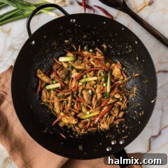 A large wok filled with freshly cooked Szechuan Chicken, steaming hot and ready to serve, showcasing its rich sauce and tender ingredients.