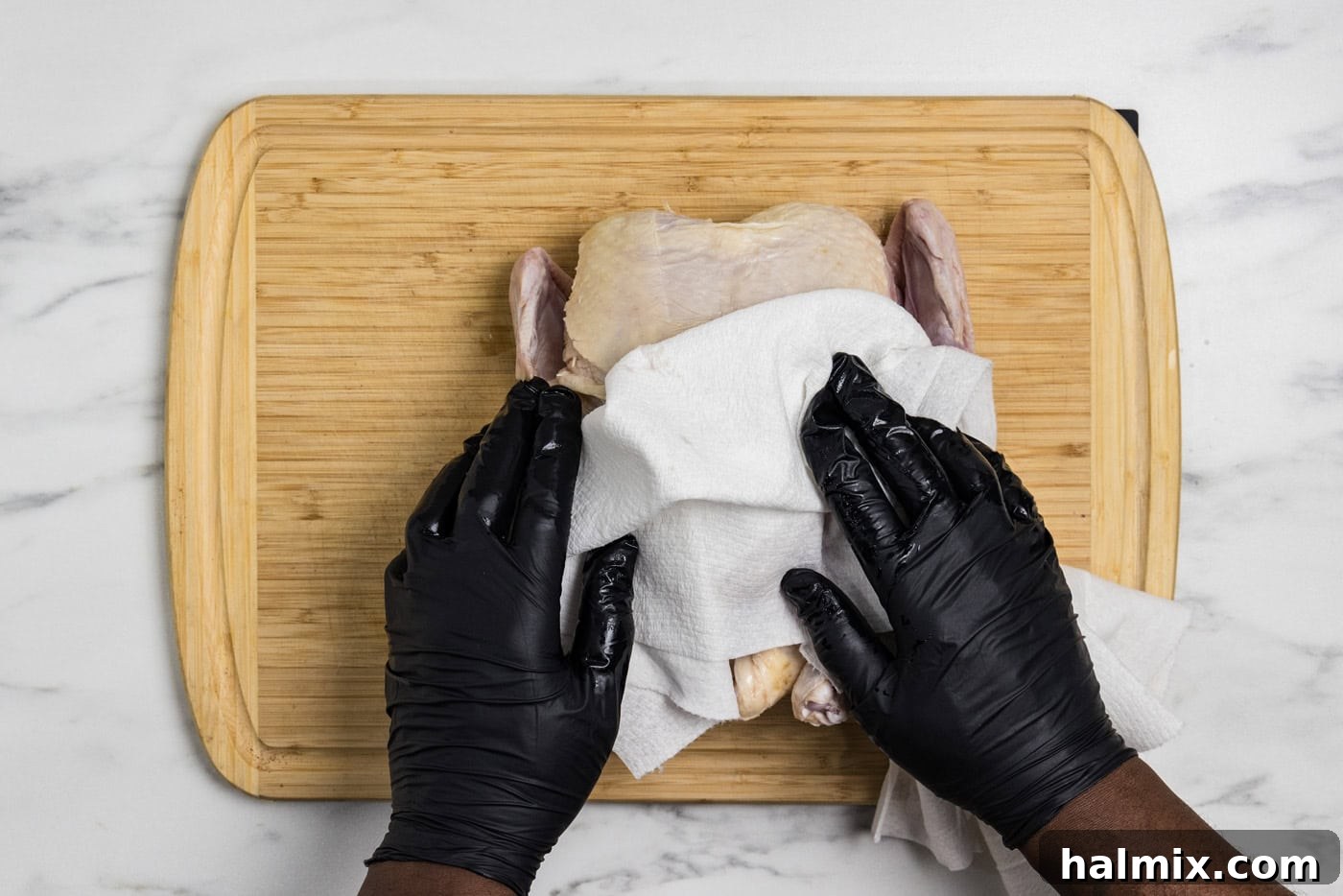 Artisan Smoked Chicken 5 Hands patting a whole raw chicken dry with paper towels