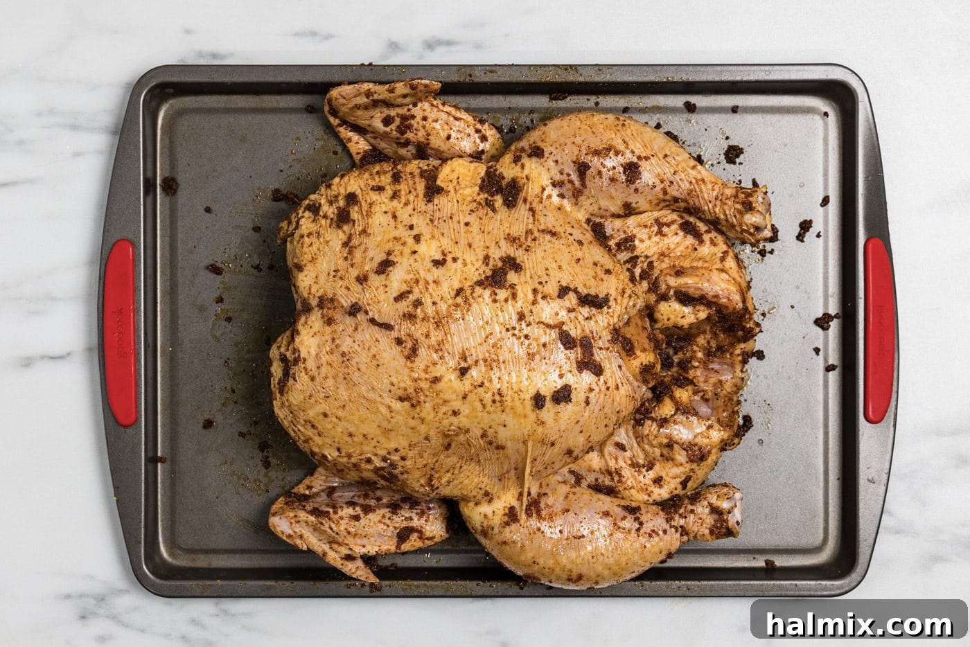 Artisan Smoked Chicken 6 Whole raw chicken coated in oil and spice rub on a baking sheet