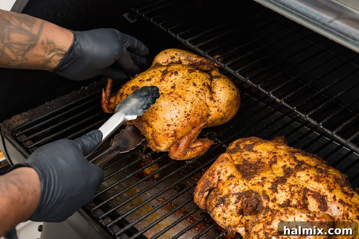 Artisan Smoked Chicken 8 Tongs flipping whole chicken upside down on a smoker grate