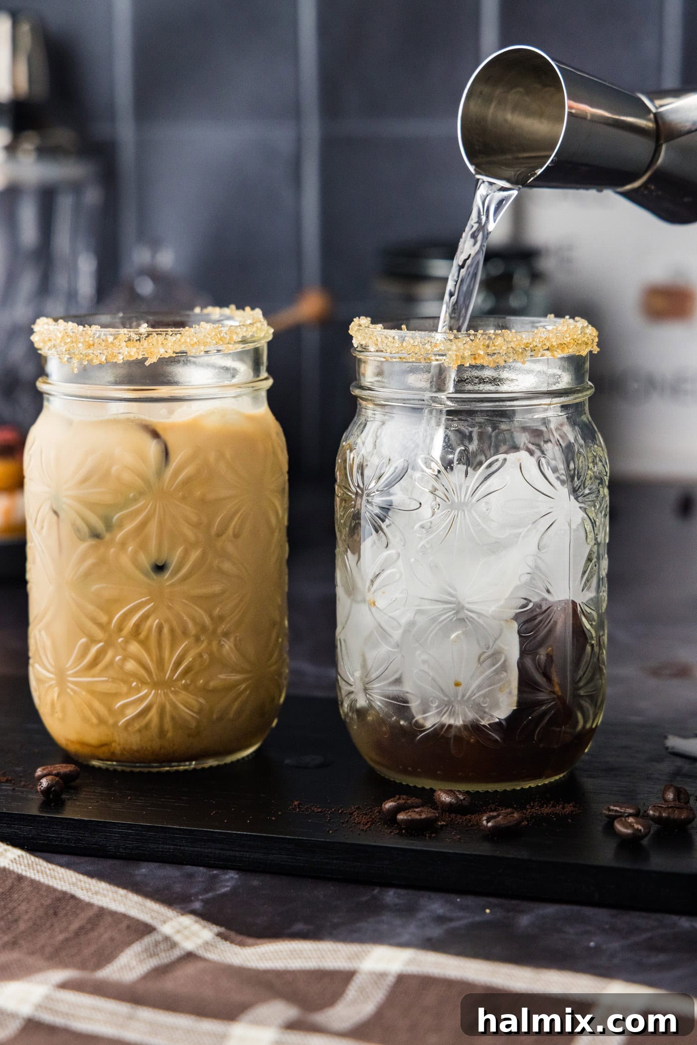 pouring vodka from jigger into a glass with ice