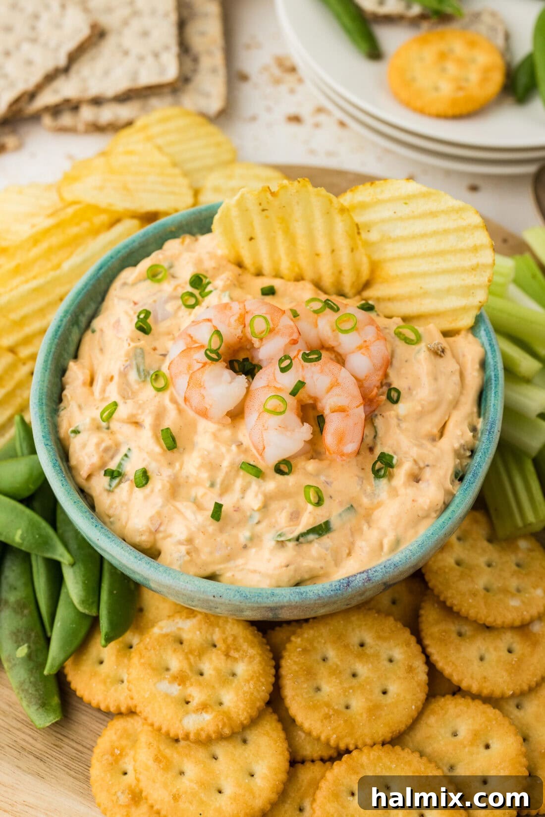 Close up photo of a bowl of Shrimp Dip with two chips in it, garnished with fresh herbs.