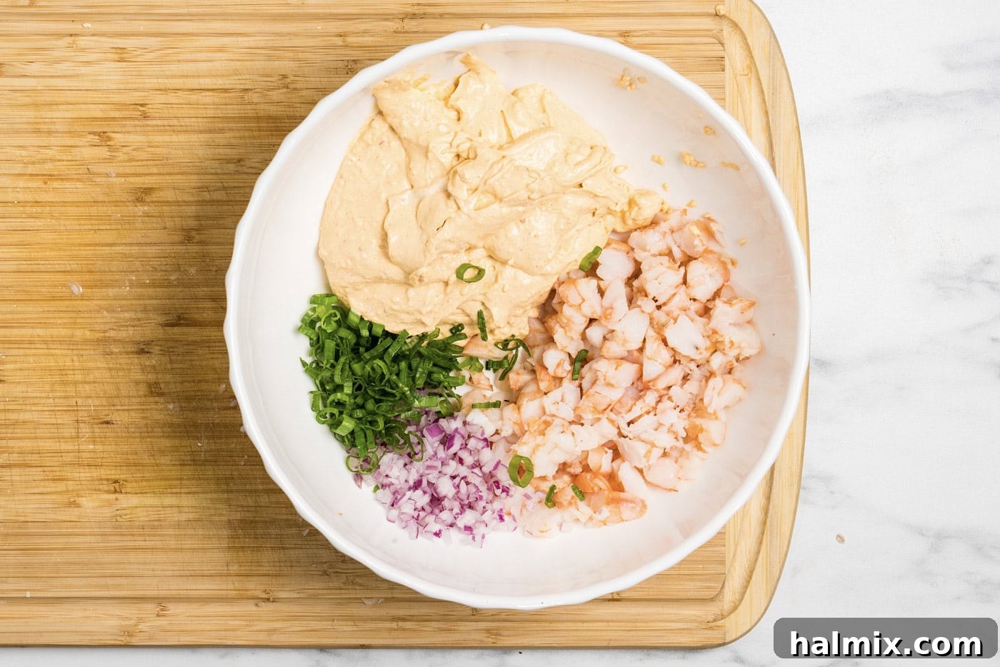 Photo of all shrimp dip ingredients mixed together in a bowl, showing the creamy texture and visible shrimp pieces.