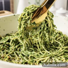 Close up photo of tongs holding up Spinach Spaghetti, highlighting the rich green sauce
