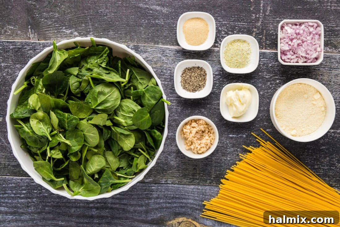 A selection of fresh ingredients laid out for Spinach Spaghetti, including spinach, pasta, butter, garlic, and shallots