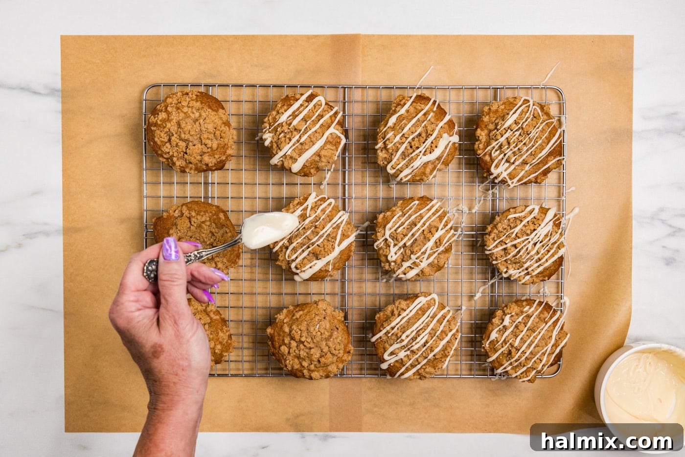 hand drizzling glaze on top of apple streusel muffins