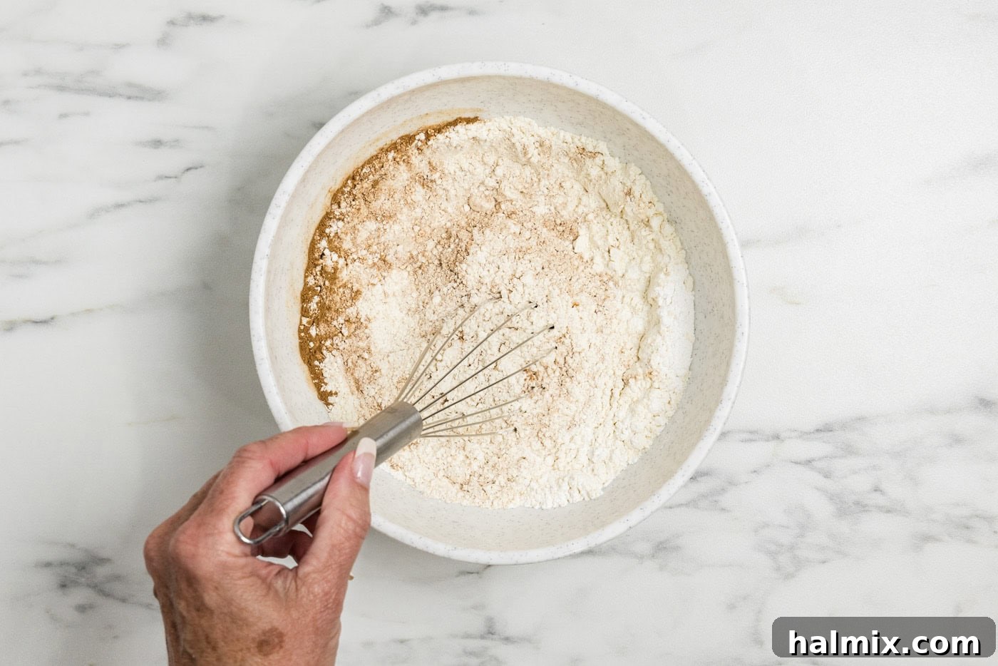 hand whisking dry ingredients in a bowl