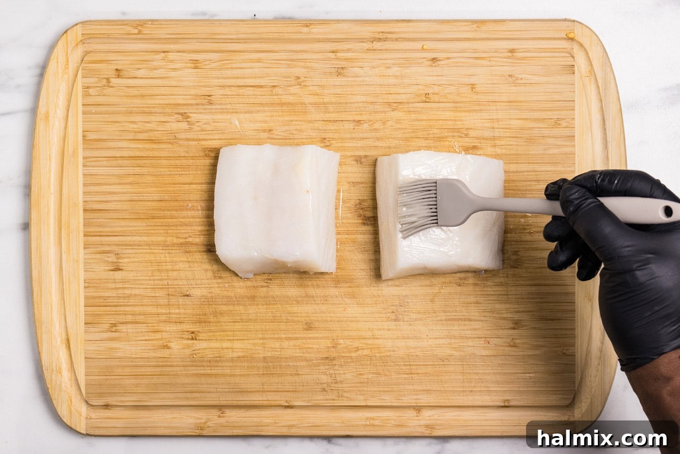 basting brush brushing melted butter onto chilean sea bass filets