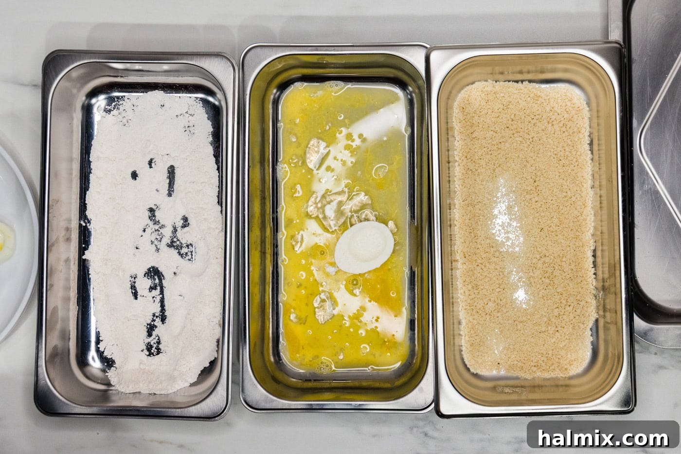 floured egg white dropped into egg wash in a breading tray