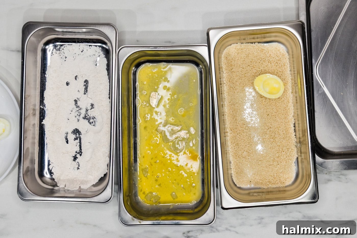 floured and dredged egg white in panko breadcrumbs inside a breading tray