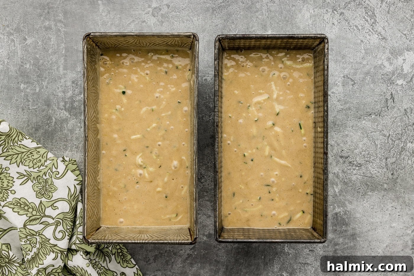 Zucchini bread batter poured into two loaf pans, ready for baking.