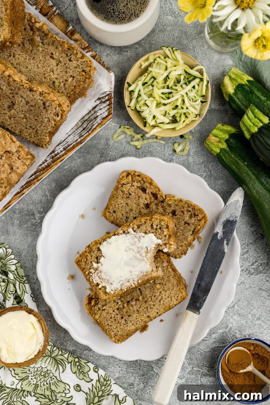 Squash Loaf 9 Slices of Zucchini Bread on a plate with one slice buttered, ready to be enjoyed.