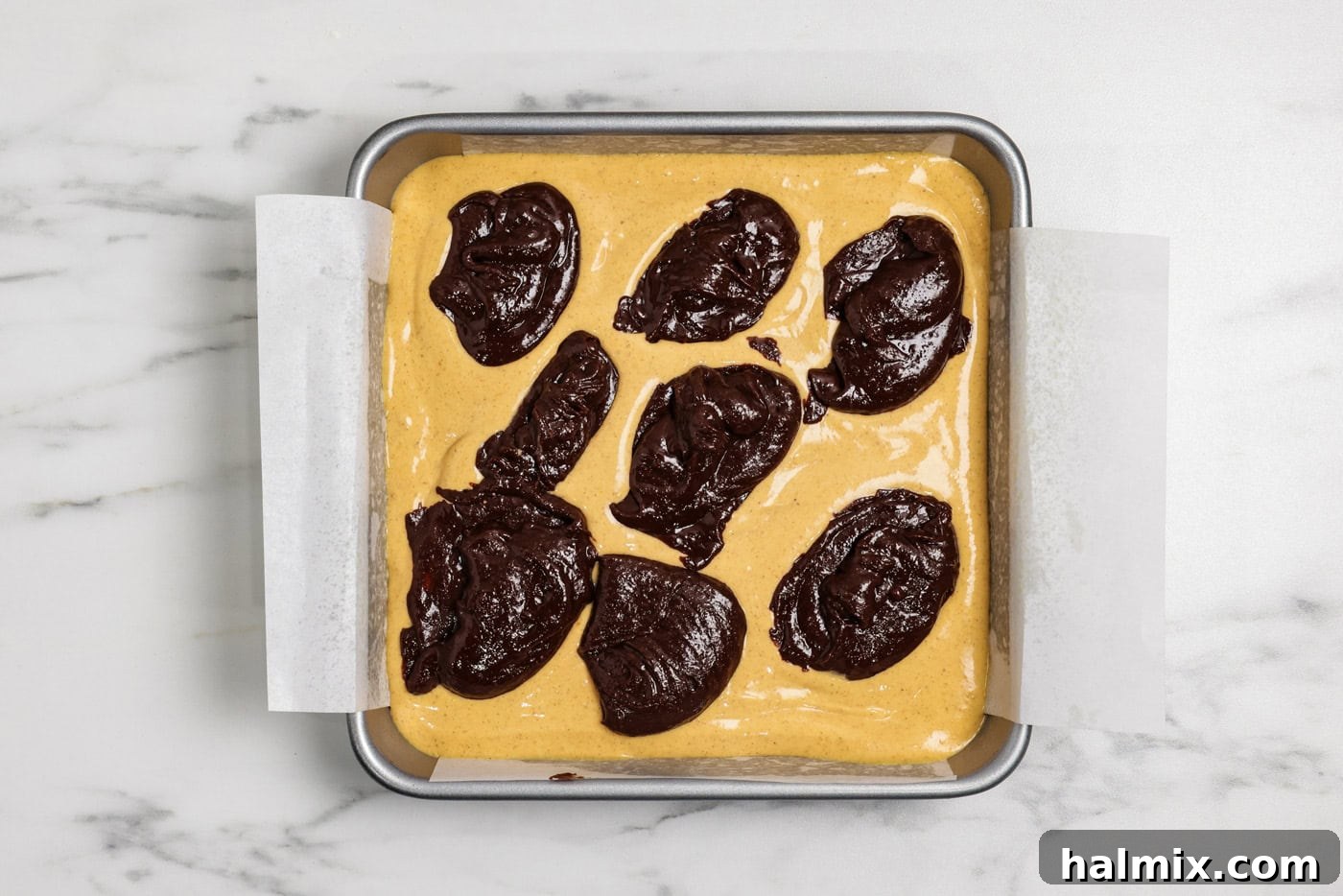 Spiced Pumpkin Swirl Brownies 13 spoonfuls of brownie batter on top of pumpkin cheesecake batter layer in a pan