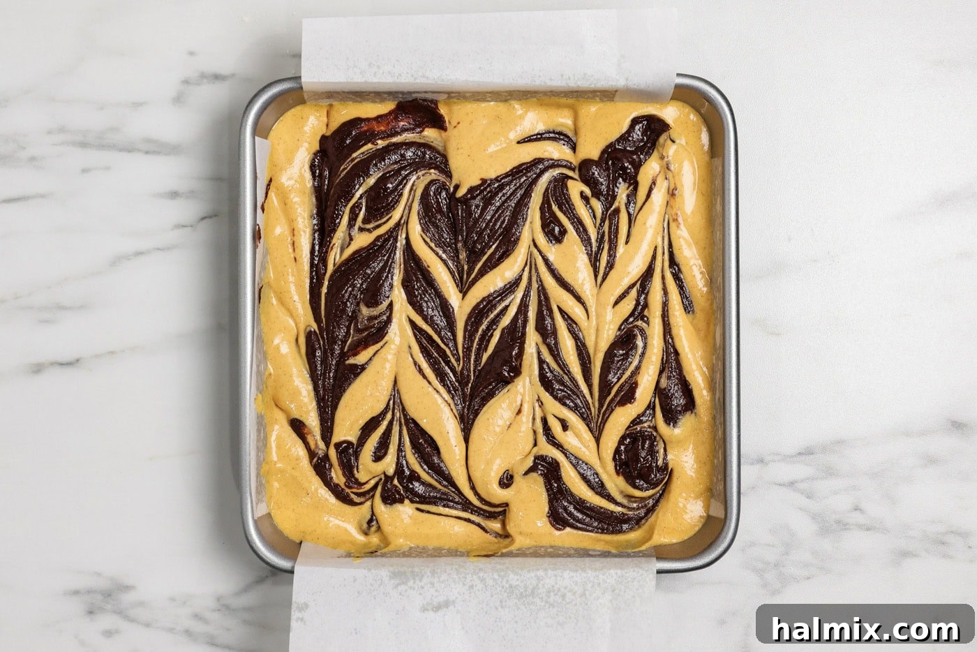 Spiced Pumpkin Swirl Brownies 15 swirls of brownie batter on top of pumpkin cheesecake batter in a pan