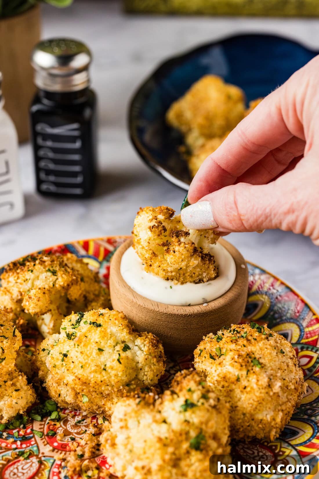 Perfectly Crispy Air Fryer Cauliflower 3 Air Fryer Fried Cauliflower being dipped into a creamy ranch sauce, highlighting its crispy texture.