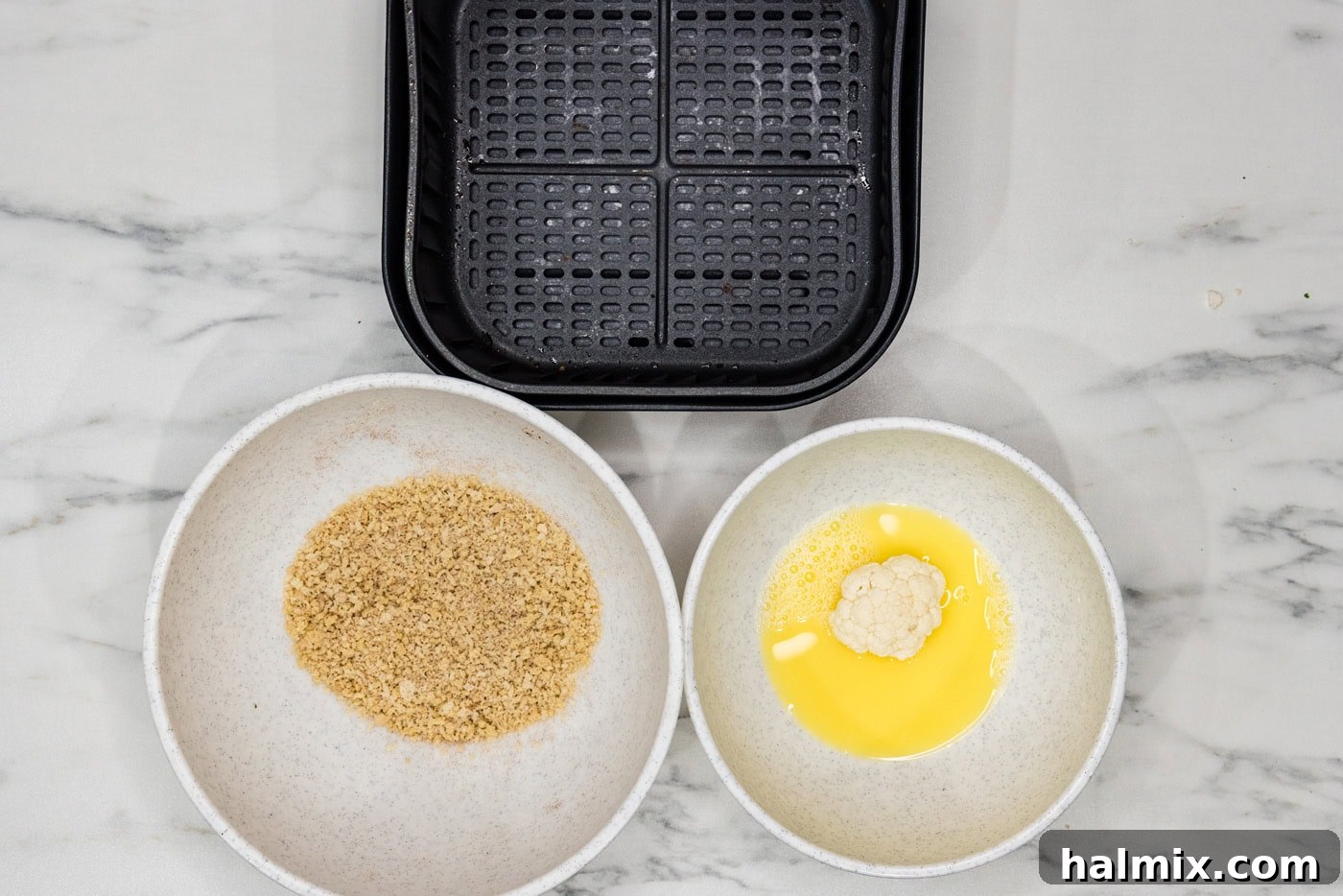 Perfectly Crispy Air Fryer Cauliflower 6 Cauliflower florets submerged in a bowl of egg and water, ready for breading.
