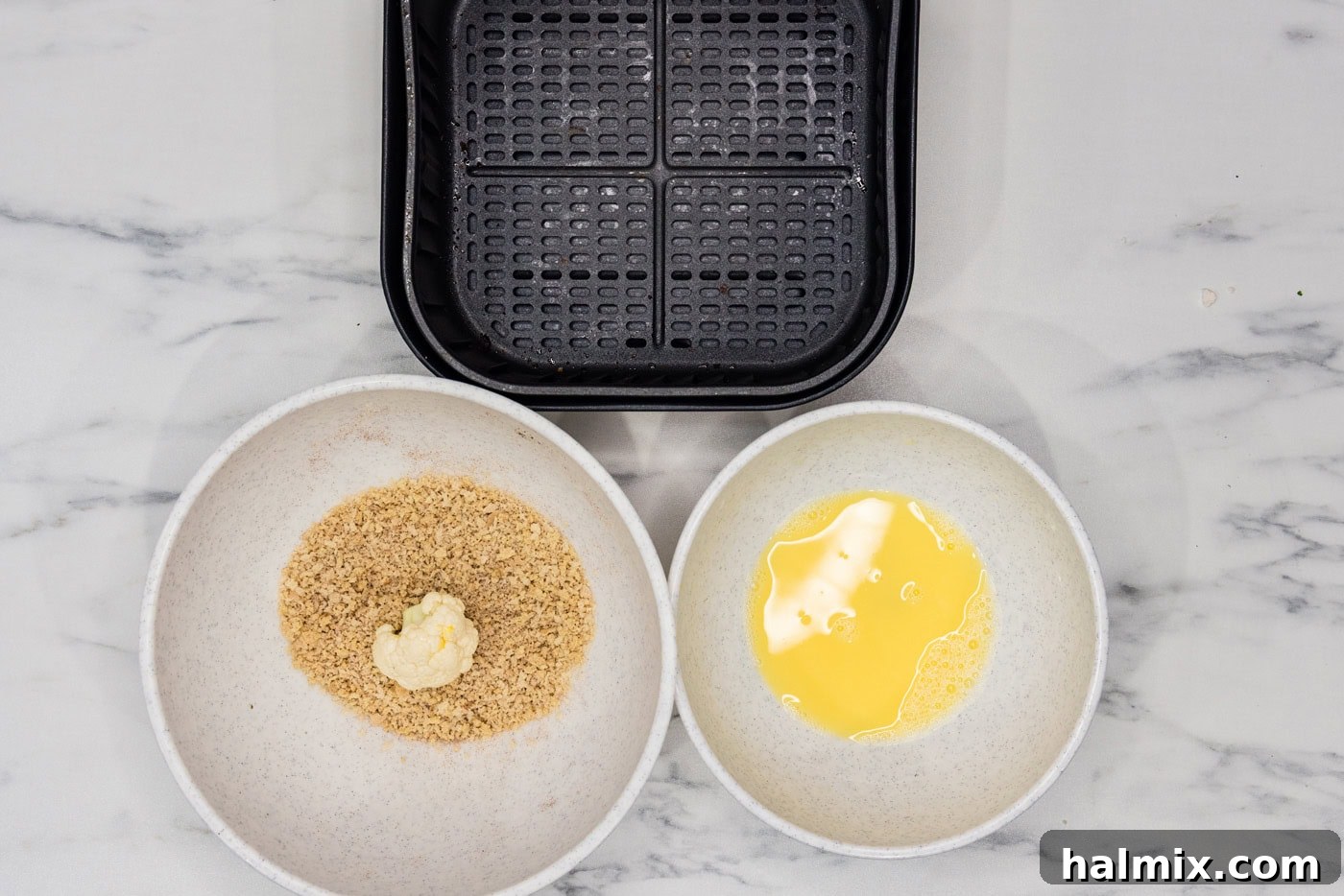 Perfectly Crispy Air Fryer Cauliflower 7 An egg-dredged cauliflower floret being coated in a bowl of panko breadcrumbs.