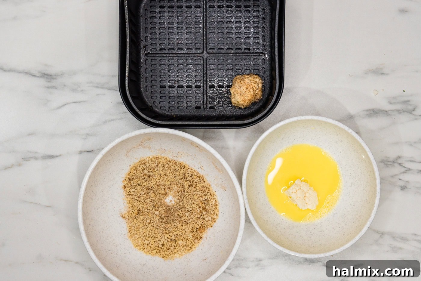 Perfectly Crispy Air Fryer Cauliflower 8 A panko-coated cauliflower floret carefully placed into an air fryer basket, alongside other florets.