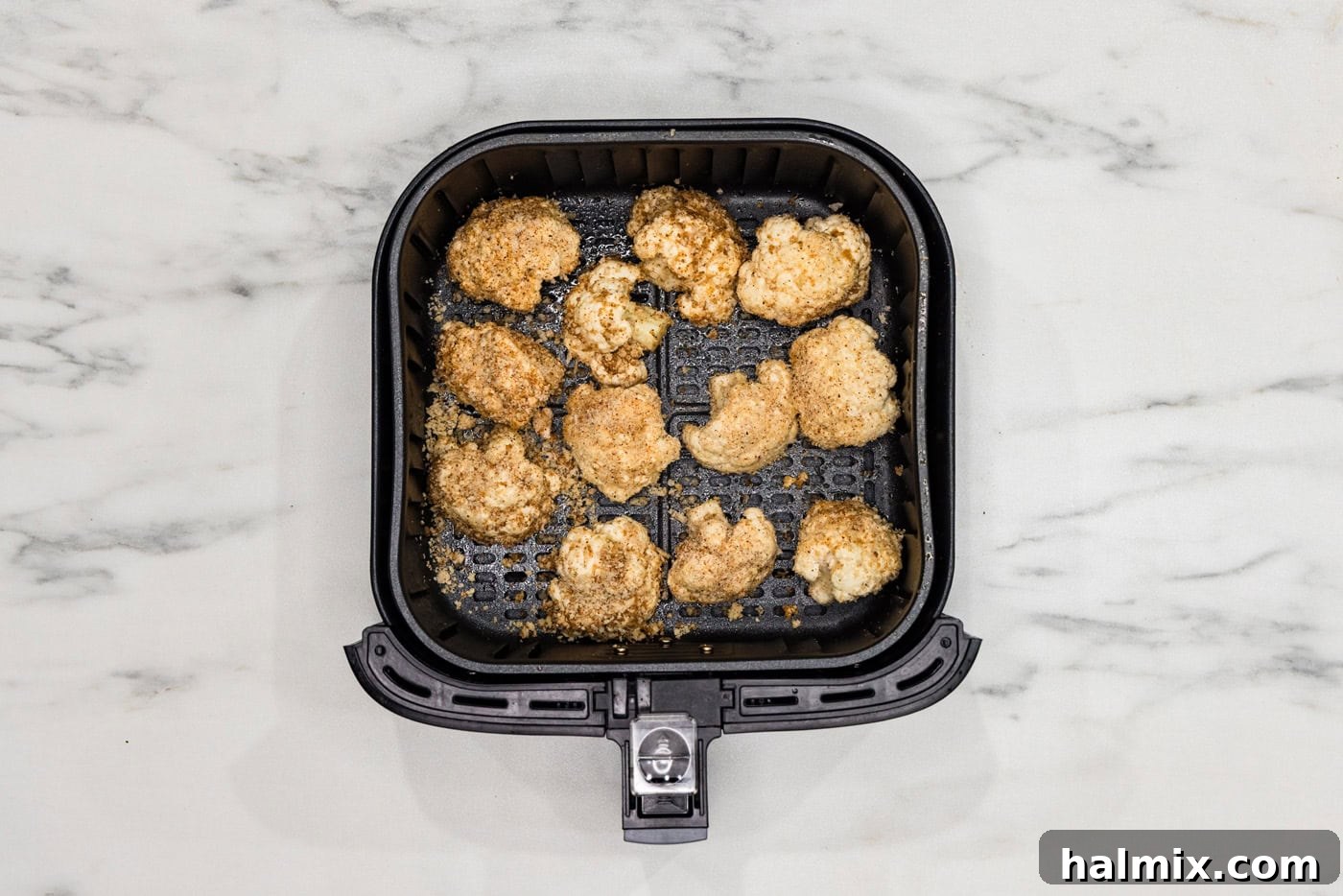 Perfectly Crispy Air Fryer Cauliflower 9 Panko-coated cauliflower florets cooking and crisping up in an air fryer basket.