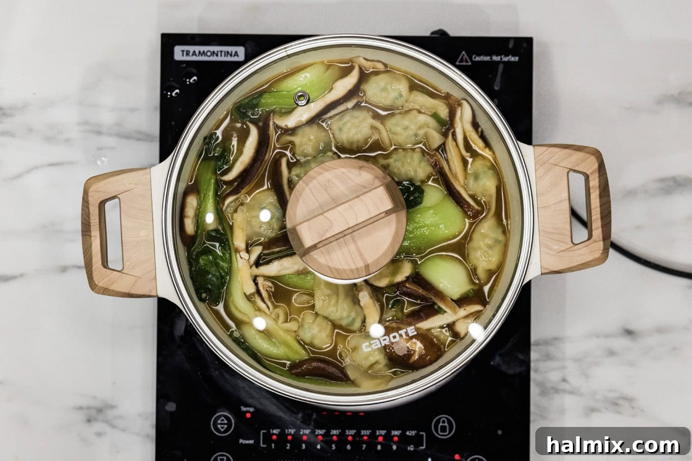 lid on stockpot with wonton soup inside, signaling it's ready to be served.