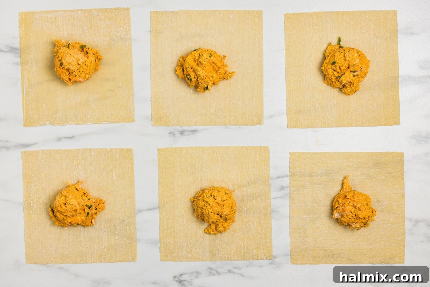 egg roll wrappers on a flat surface with buffalo chicken mixture on top