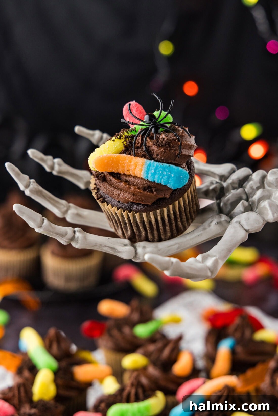 Skeleton hand holding a Halloween Dirt Cupcake with gummy worms