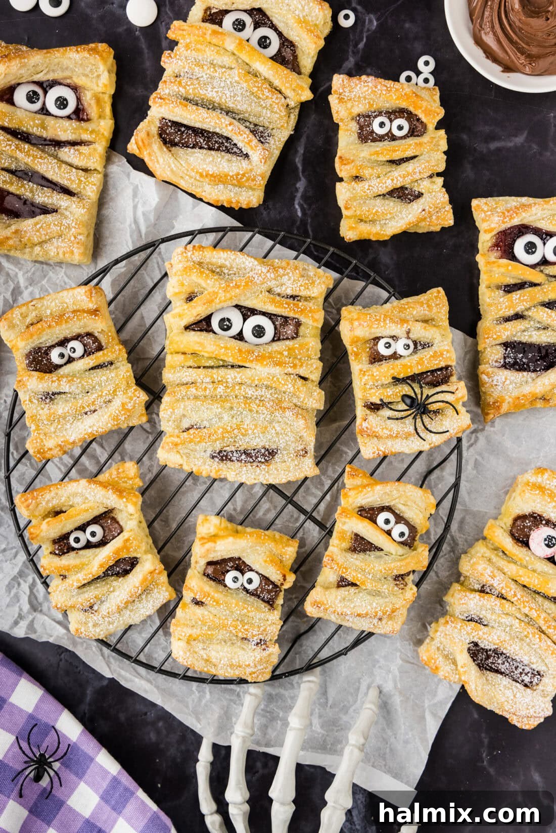 Mummy Hand Pies resting on a wire rack, freshly baked and ready for decorating