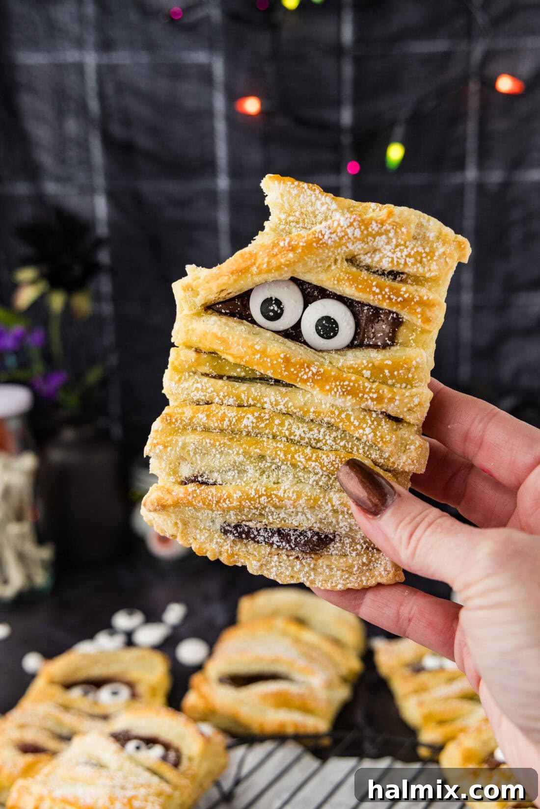 Hand holding a Mummy Hand Pie with a bite taken out, revealing the strawberry jam filling