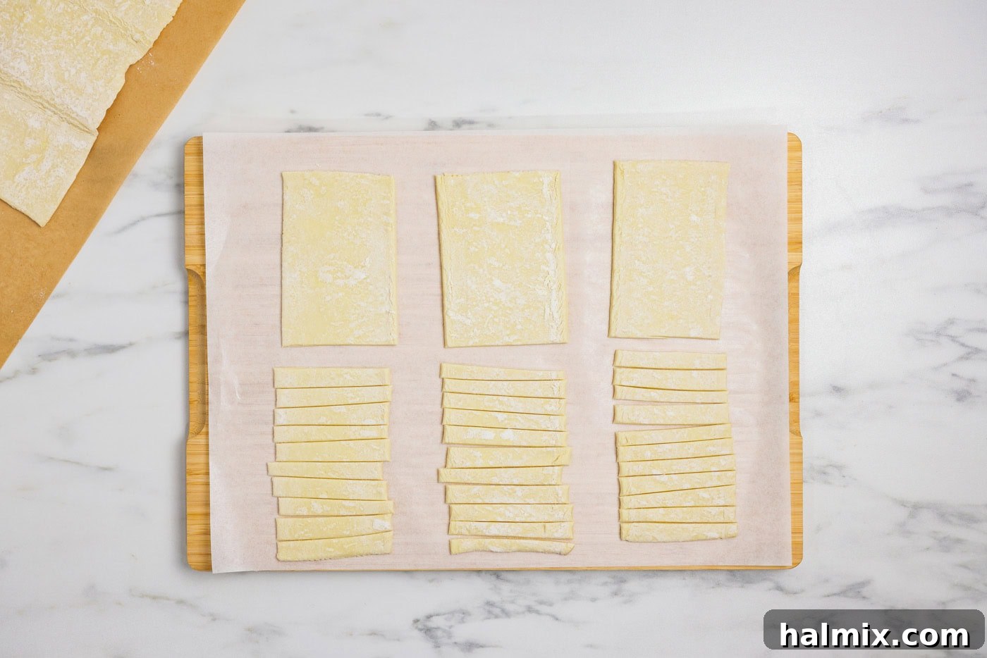 Puff pastry cut into rectangular sections and thin strips on a cutting board, ready for assembly