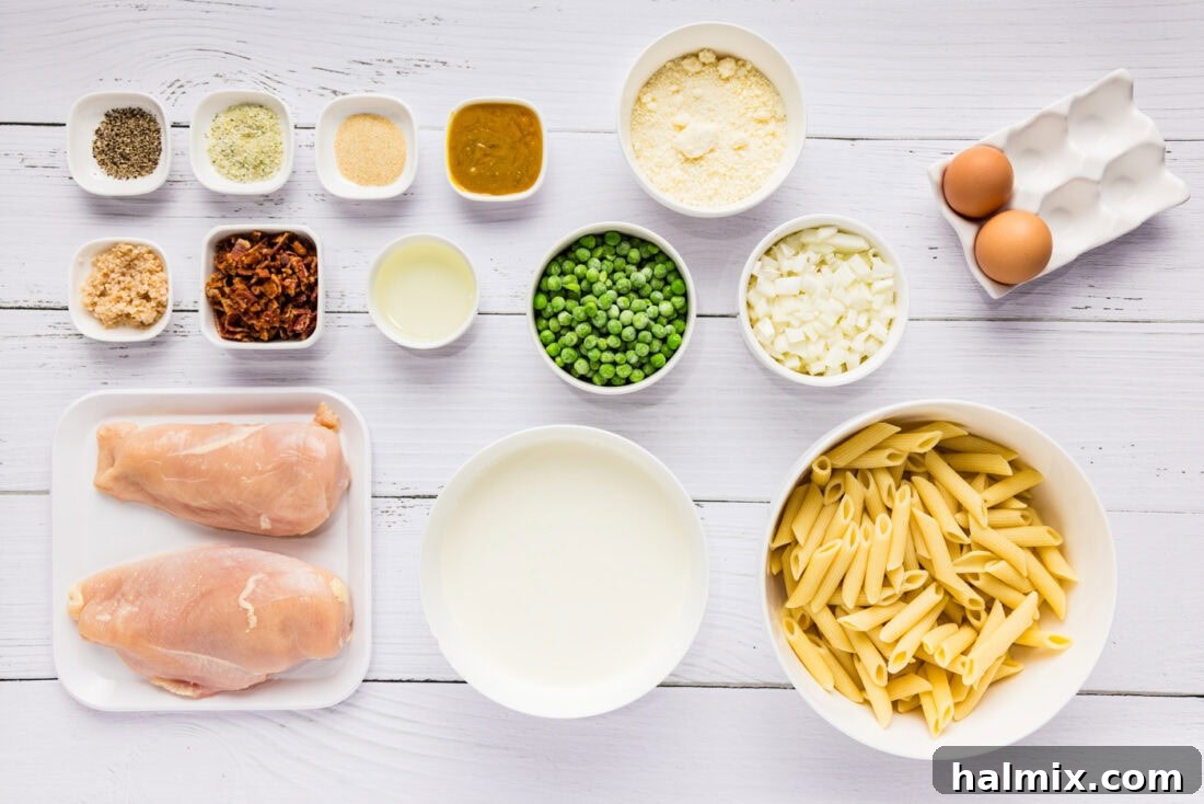 A collection of fresh ingredients laid out, including pasta, chicken breasts, eggs, heavy cream, garlic, onion, peas, and bacon, ready for Chicken Carbonara preparation.