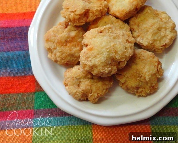 A close-up overhead photo of golden brown, perfectly crispy homemade chicken nuggets on a white plate, ready to be enjoyed.