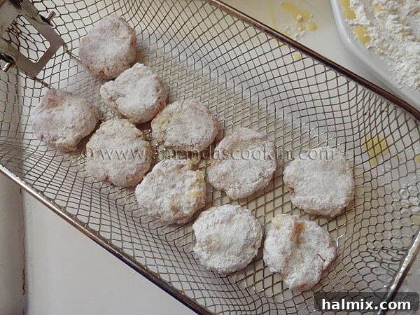 Raw chicken nuggets carefully placed in a metal frying basket, ready to be lowered into hot oil.