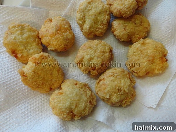 An overhead shot of freshly fried, golden chicken nuggets draining on a paper towel-lined plate to absorb excess oil.