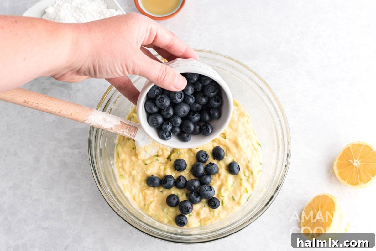 adding blueberries to the zucchini bread batter, preparing for a gentle fold