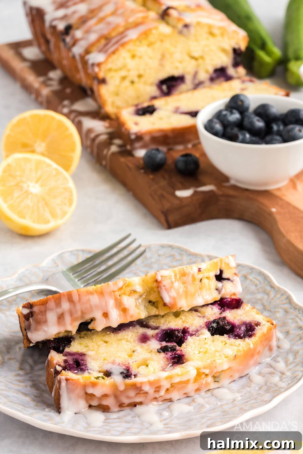 two slices of lemon zucchini bread on a plate, showing the moist texture and juicy blueberries