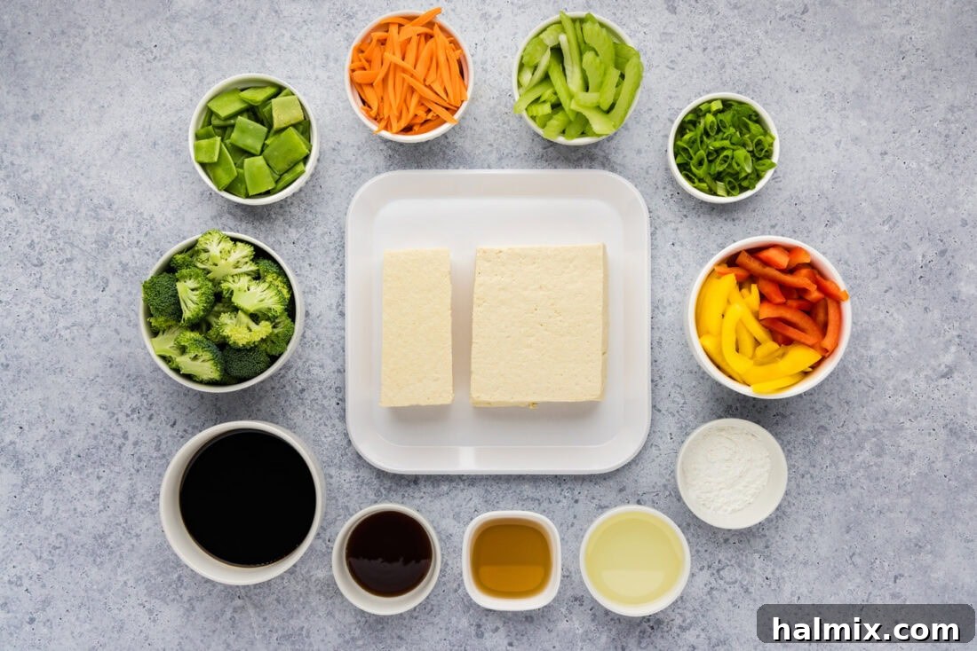 Golden Tofu Stir-Fry 4 Ingredients laid out for Tofu Stir Fry, including fresh vegetables, tofu block, and sauces.