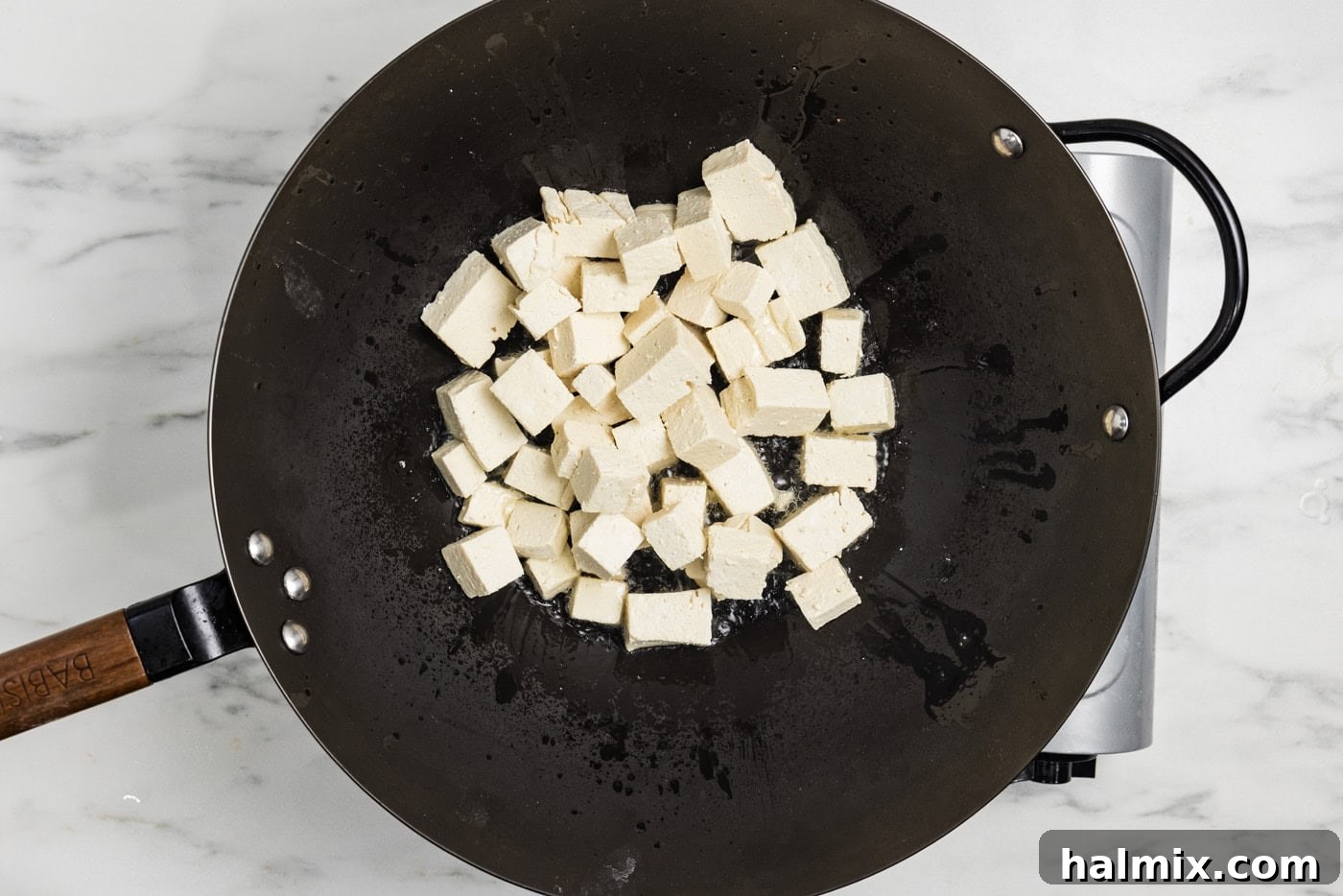 Golden Tofu Stir-Fry 6 Cornstarch coated tofu cubes browning in a wok, achieving a desirable golden crust.
