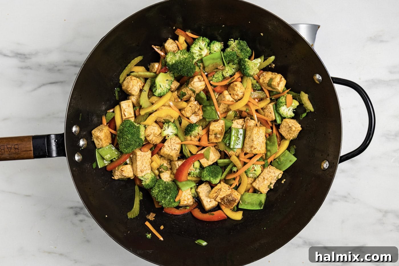 Golden Tofu Stir-Fry 9 Cooked tofu stir fry in a wok, perfectly coated in a savory sauce and ready to serve.