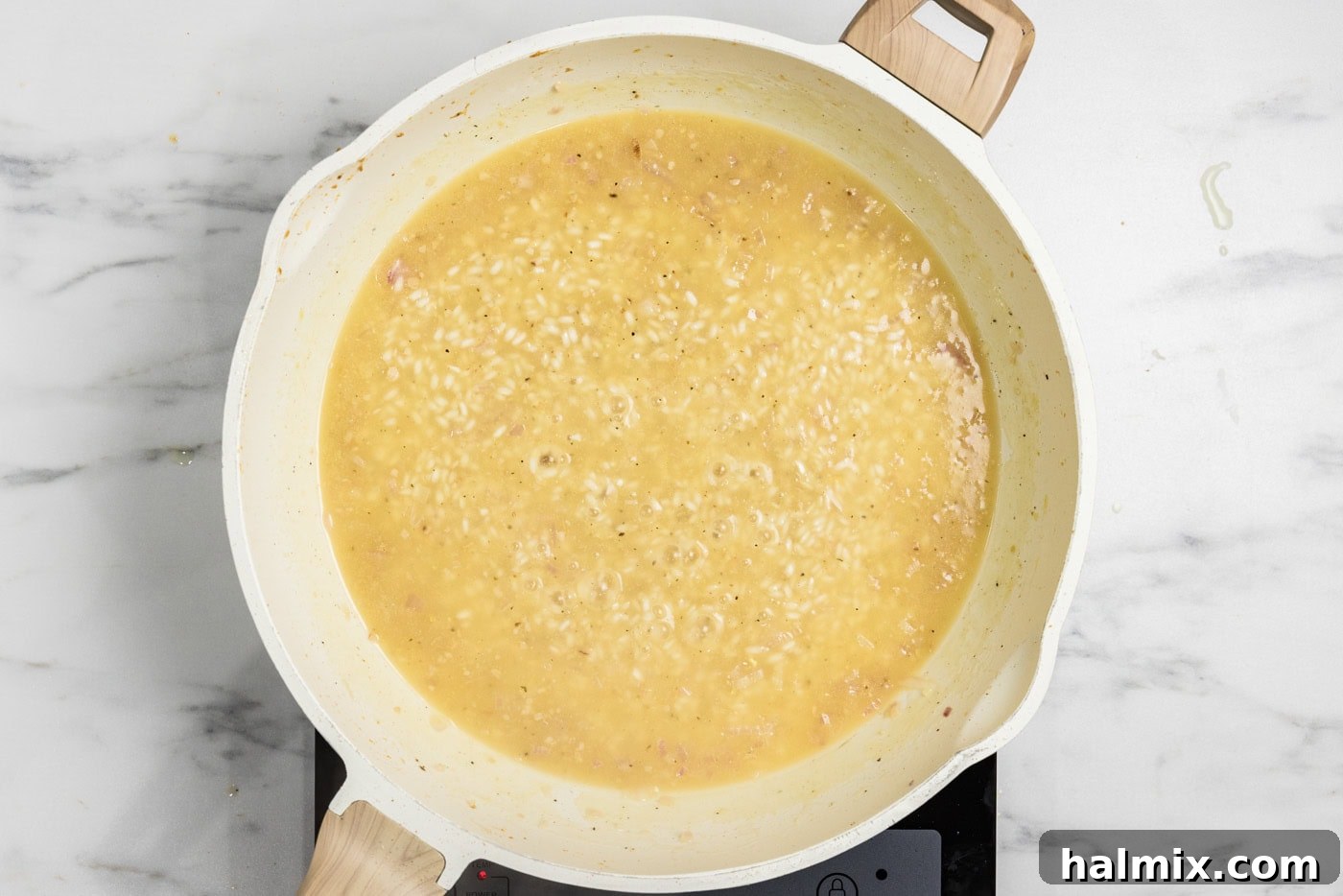 Creamy Prawn Risotto 9 Warm chicken broth being added to a skillet with creamy risotto.