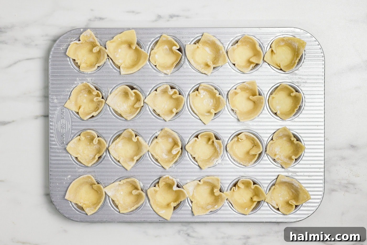 puff pastry squares tucked inside cavities on a mini muffin tin
