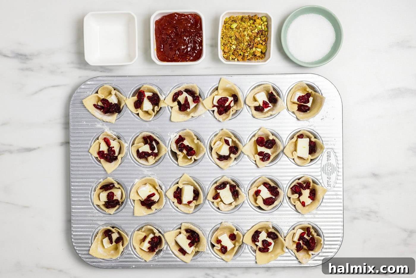 Petite Brie 8 dried cranberries added to brie bites in a mini muffin pan