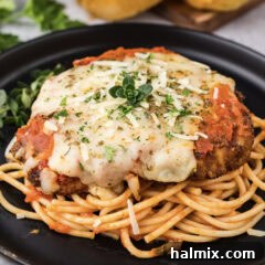 Close up photo of Veal Parmesan plated on top of spaghetti