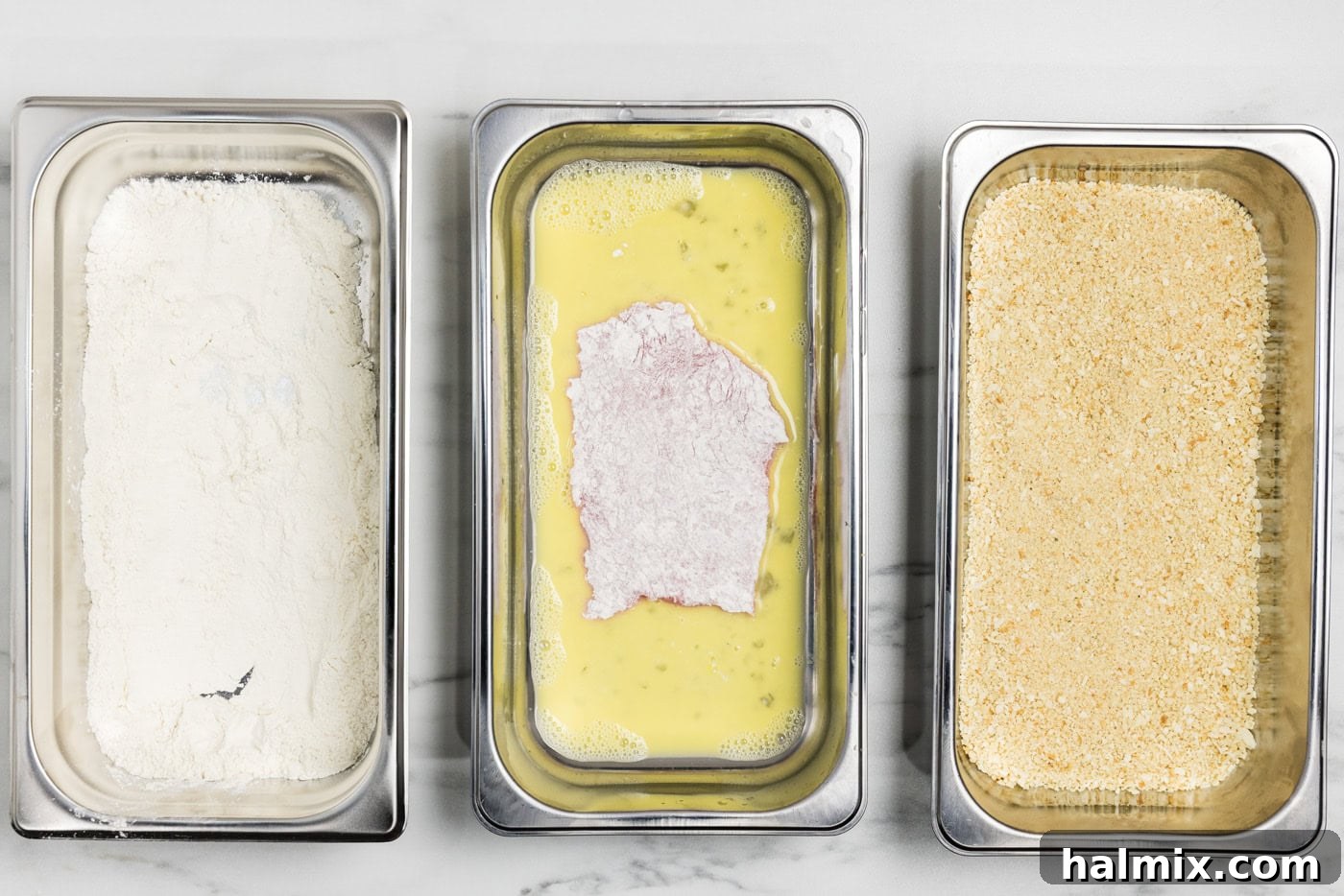 floured veal cutlets in breading tray with egg