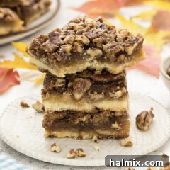 Close up photo of a stack of Pecan Pie Bars with a bite taken out of one, highlighting the detailed texture.