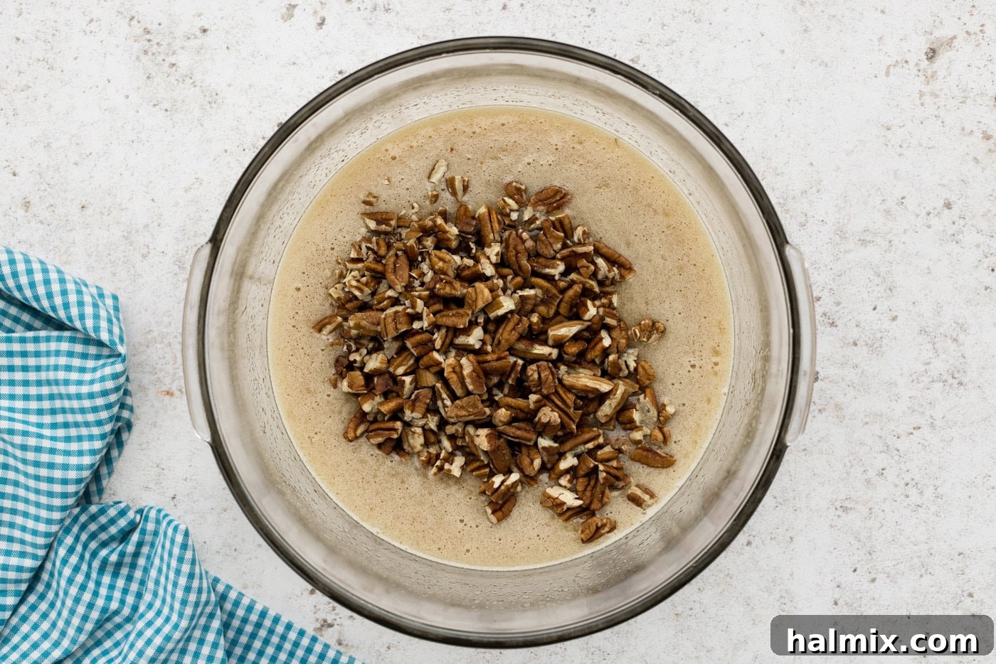 Decadent Pecan Pie Squares 8 Chopped pecans being added to the pecan pie filling in a mixing bowl, folded in gently.