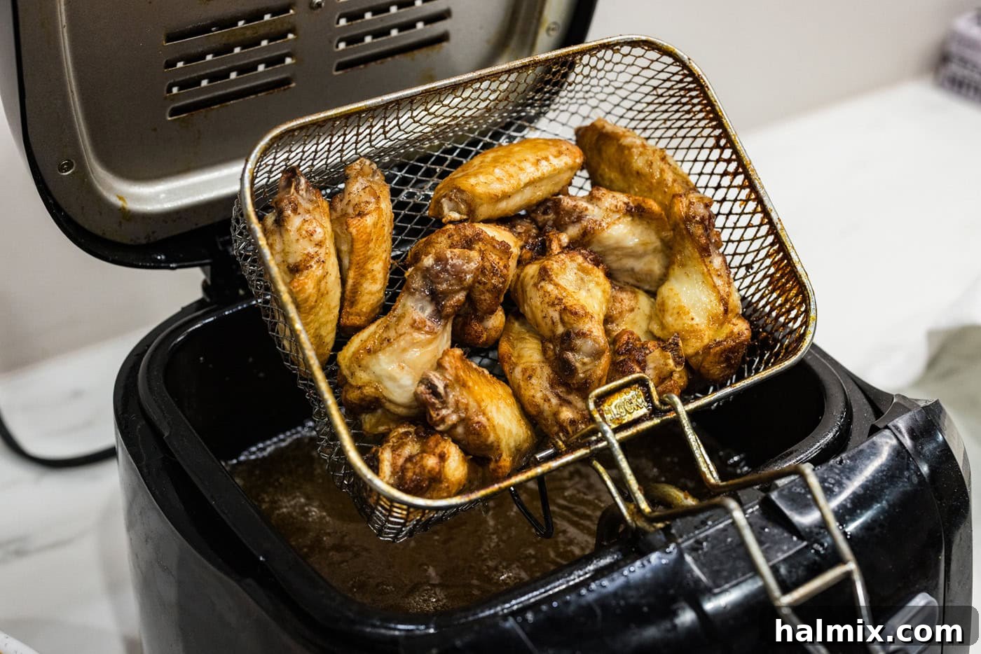 removing basket of chicken wings from a deep fryer