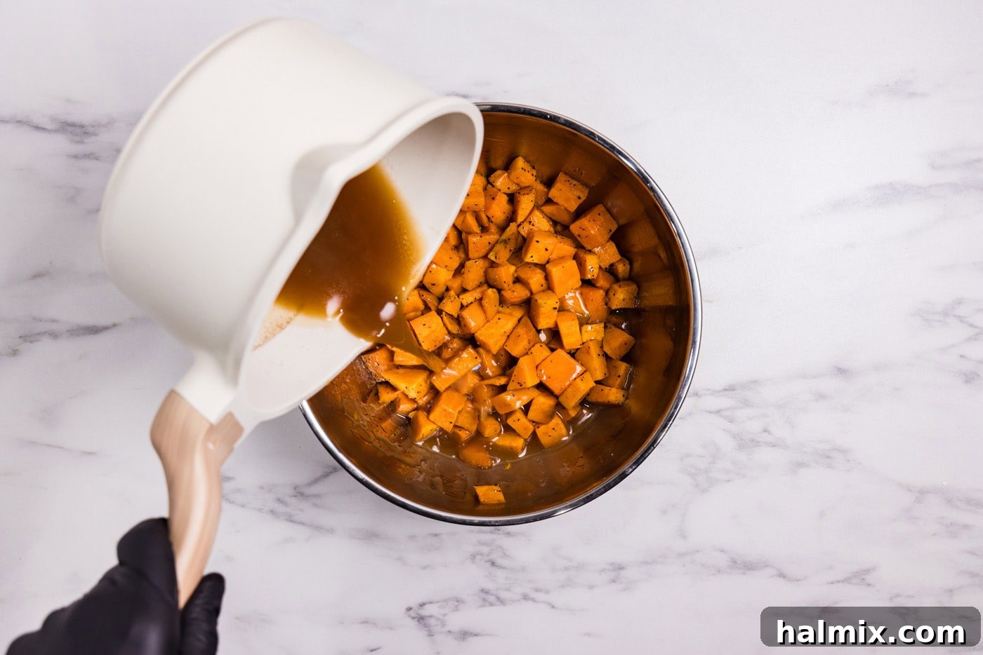Bourbon Glazed Sweet Potatoes 10 pouring sauce over cubed sweet potatoes in a bowl