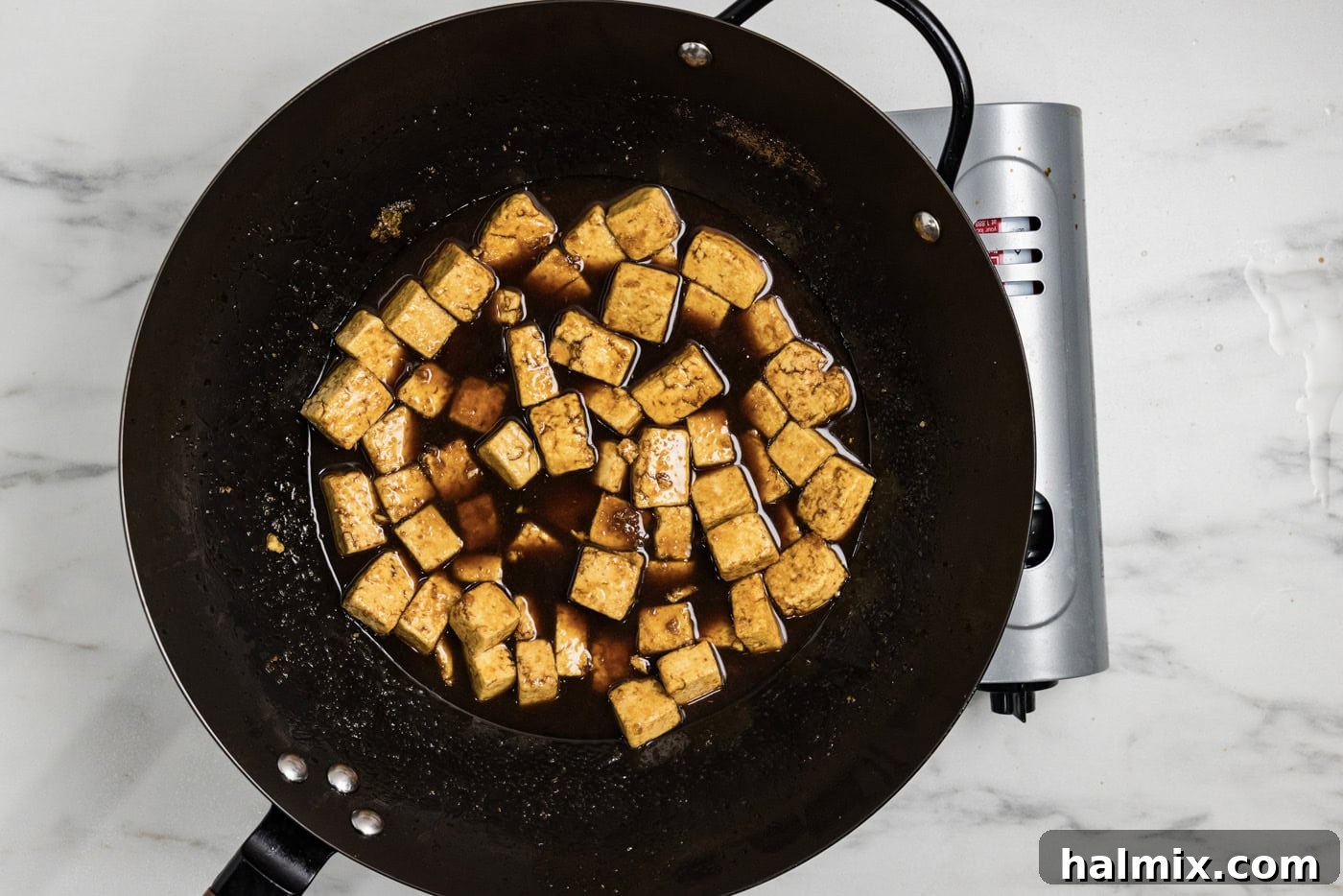 stir fried tofu in a wok with teriyaki sauce